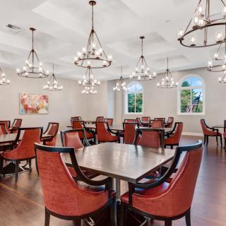 A spacious and elegantly decorated dining room with chandeliers and red chairs.