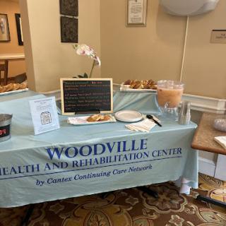A welcoming setup for the Woodville Health and Rehabilitation Center at a community event, featuring snacks and informational materials.