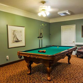 A cozy game room featuring a classic billiards table with green felt, surrounded by walls adorned with artwork.