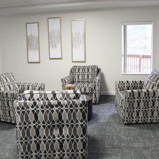 A modern living room with patterned armchairs and minimalist wall art.