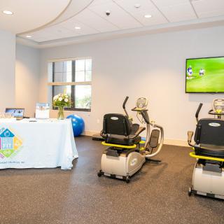 A fitness center room with exercise bikes and a television on the wall.