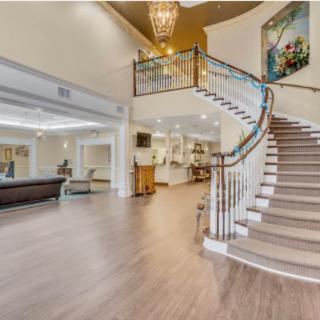 A spacious and modern lobby featuring a grand staircase, elegant chandelier, and contemporary artwork.