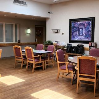An empty dining room with several tables and chairs, featuring a framed artwork on the wall.