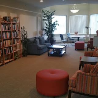 A cozy lounge area with a bookshelf, comfortable seating, and indoor plants, perfect for relaxation or reading.