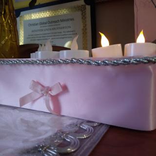 A decorative arrangement featuring illuminated candles on a pink base, adding a warm glow to the setting.