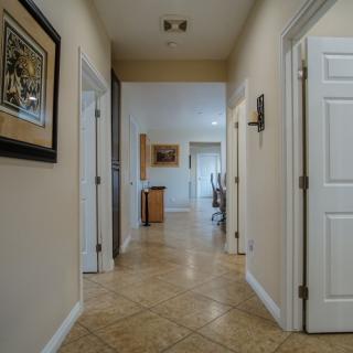 A view down a well-lit hallway with tile flooring and several doors leading to different rooms.