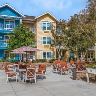 A colorful apartment building with outdoor seating and umbrellas in a residential area.