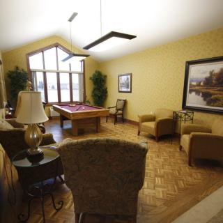 A cozy living room featuring a pool table, armchairs, and vibrant artwork.