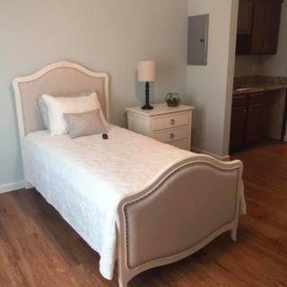 A minimalist bedroom with a single bed and nightstand on a hardwood floor.
