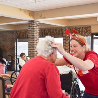 A caregiver playfully interacts with a senior resident, sharing a joyful moment together.