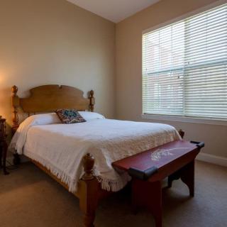 A cozy bedroom with a large bed and natural light filtering through the window.