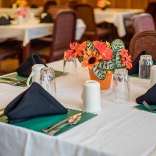 A neatly arranged dining table with floral centerpiece and place settings.