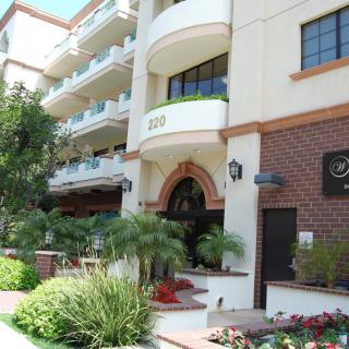 The exterior of a hotel building with balconies, surrounded by well-maintained landscaping and greenery.