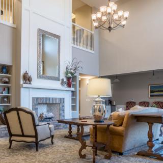 A spacious living room with high ceilings, featuring elegant furniture and a central fireplace.