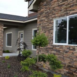 A modern house with a stone facade and landscaped garden.