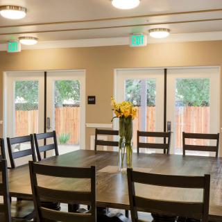 A cozy dining room with a wooden table and chairs, adorned with a vase of flowers.
