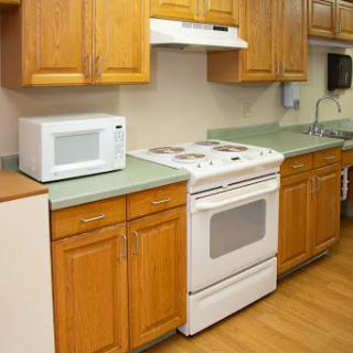 A tidy kitchen featuring a microwave, stove, and wooden cabinets.