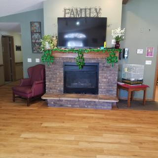 A cozy living room with a fireplace, television, and an armchair.