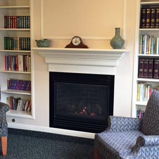 A cozy living room with a fireplace flanked by bookshelves and armchairs.