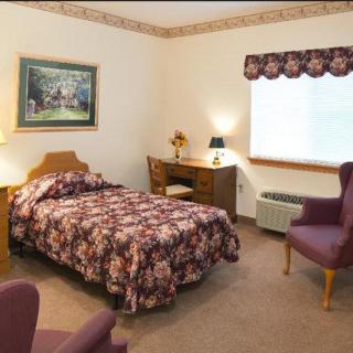 A cozy bedroom with a single bed, desk, and seating area.