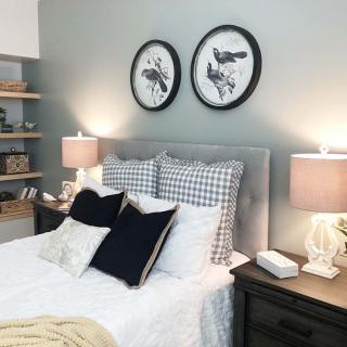 A modern bedroom with stylish decor, featuring a comfortable bed, decorative pillows, and framed wall art.