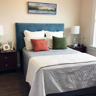 A neatly arranged bedroom with a double bed, colorful pillows, and matching nightstands with lamps.
