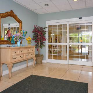 A welcoming lobby with a decorative table and mirror beside glass entrance doors.