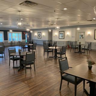 An empty dining room with several tables and chairs arranged neatly on a wooden floor.