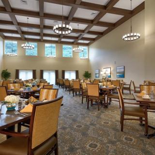 Spacious modern dining area with elegant chandeliers and neatly arranged tables and chairs.