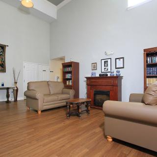A cozy living room with sofas, a fireplace, bookshelves, and wooden flooring.