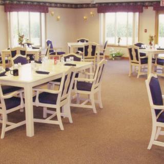 A spacious dining room with multiple tables and chairs, surrounded by large windows.