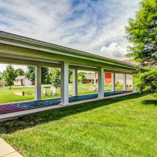 A covered walkway surrounded by lush green lawns and trees under a partly cloudy sky.
