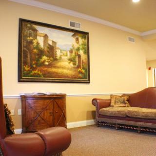 A cozy living room with a sofa and a large painting on the wall.
