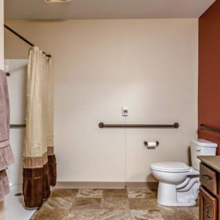 A spacious bathroom with a shower area, toilet, and sink.