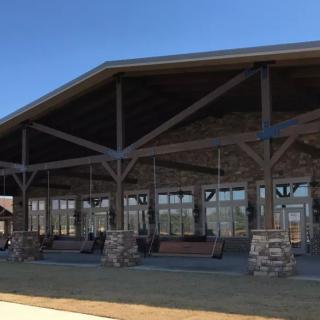 A wooden pavilion with stone pillars under a clear blue sky.