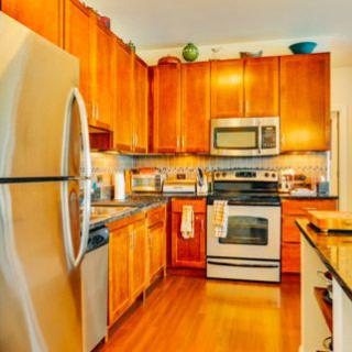 A modern kitchen with wooden cabinets and stainless steel appliances, featuring a refrigerator, oven, and microwave.