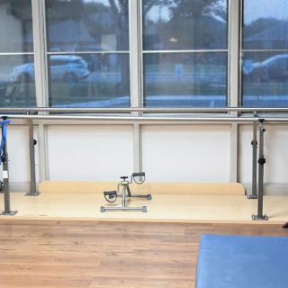 A physical therapy room featuring parallel bars and rehabilitation equipment.