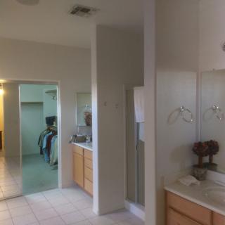 A spacious bathroom with a large mirror, double sinks, and tiled flooring.