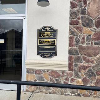 A business directory sign mounted on a stone wall outside an office building.