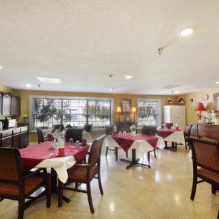 A well-lit dining area with neatly arranged tables and chairs, featuring large windows that allow natural light to fill the space.