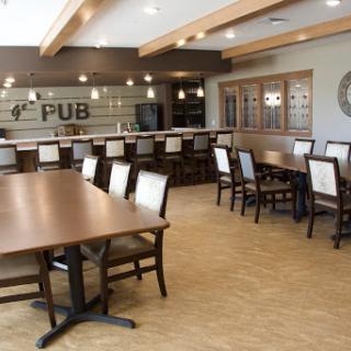 A cozy pub interior featuring wooden tables and chairs, with a welcoming bar area.
