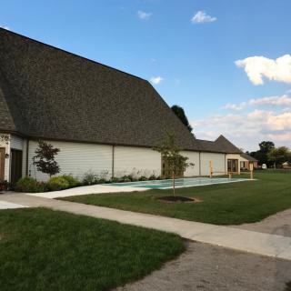 A suburban house with a well-kept lawn and sidewalk under a clear sky.