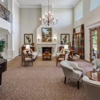 A spacious and elegantly furnished living room with a chandelier, fireplace, and grand piano.