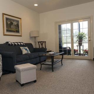 A cozy living room featuring a comfortable sofa, glass coffee table, and floor lamp, with French doors leading to an outdoor area.