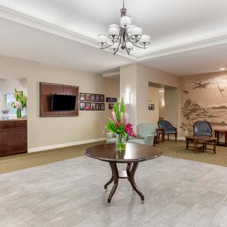 A welcoming lobby with a central table adorned with flowers, elegant chandelier lighting, and comfortable seating.