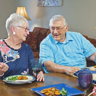 An elderly couple enjoying a meal together at home.