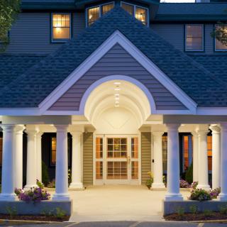 An elegant building entrance with symmetrical columns lit up in the evening.