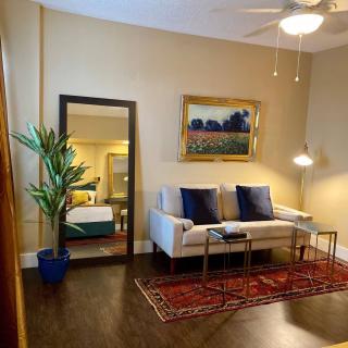 Cozy living room with a sofa, large mirror, and decorative elements like a potted plant and artwork.