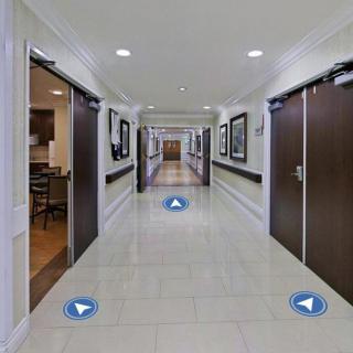 A modern, well-lit indoor hallway with multiple doors and tiled flooring.