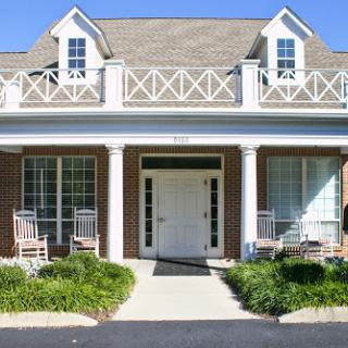 A charming house with a welcoming front porch, surrounded by well-maintained landscaping.